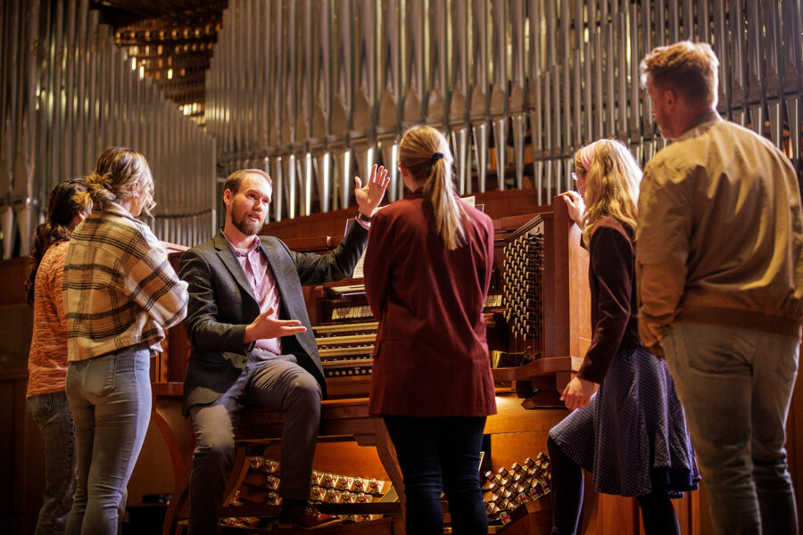 Professor instructing students by an organ