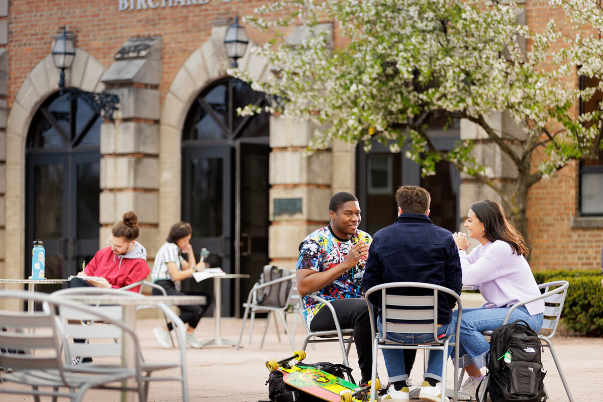 Group of students conversing in front of Birchard Gymnasium