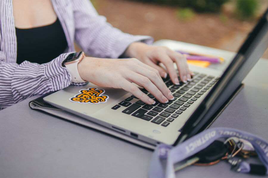 Student typing on laptop outdoors