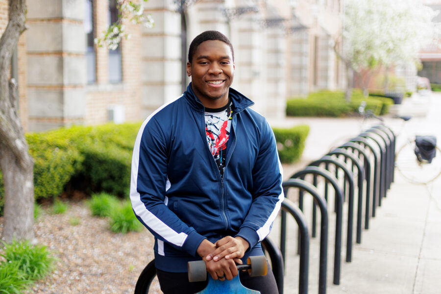 Smiling student poses with his skateboard