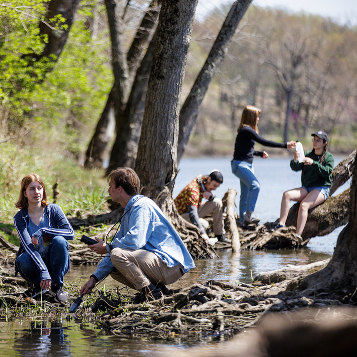 Photo of group of students conducting an experiment by the river