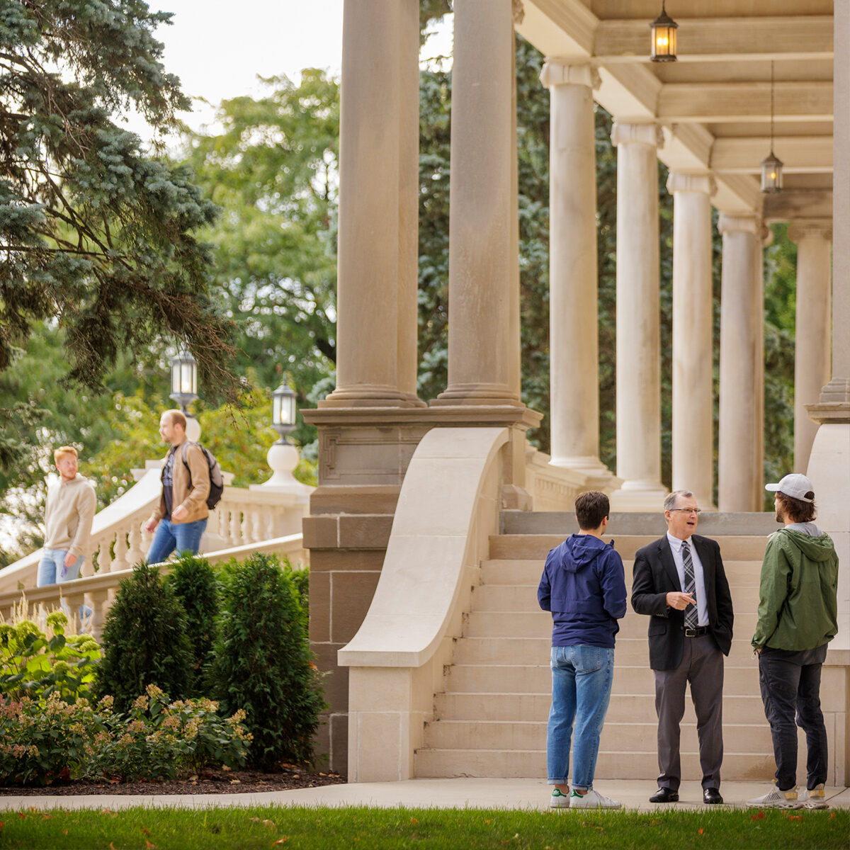 Image of professor engaging in conversation with students outside of Burke