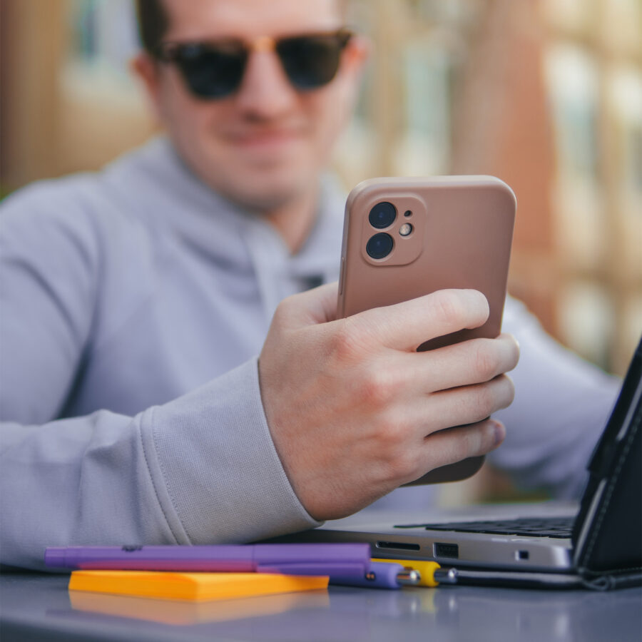 Man texting on his phone while sitting a outdoor table.