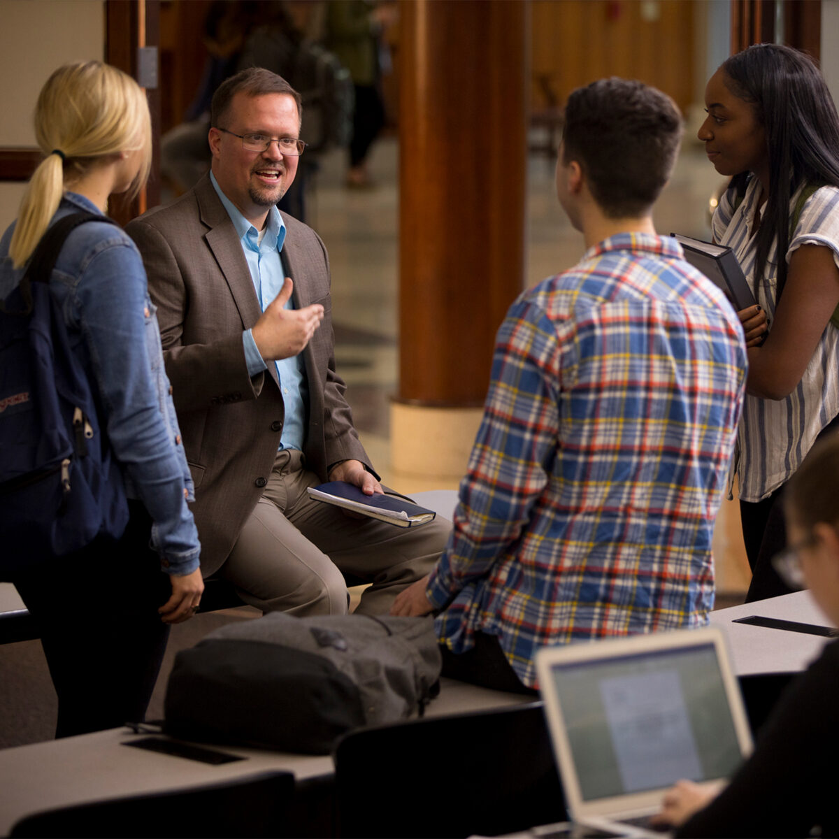 Male professor conversing with two students