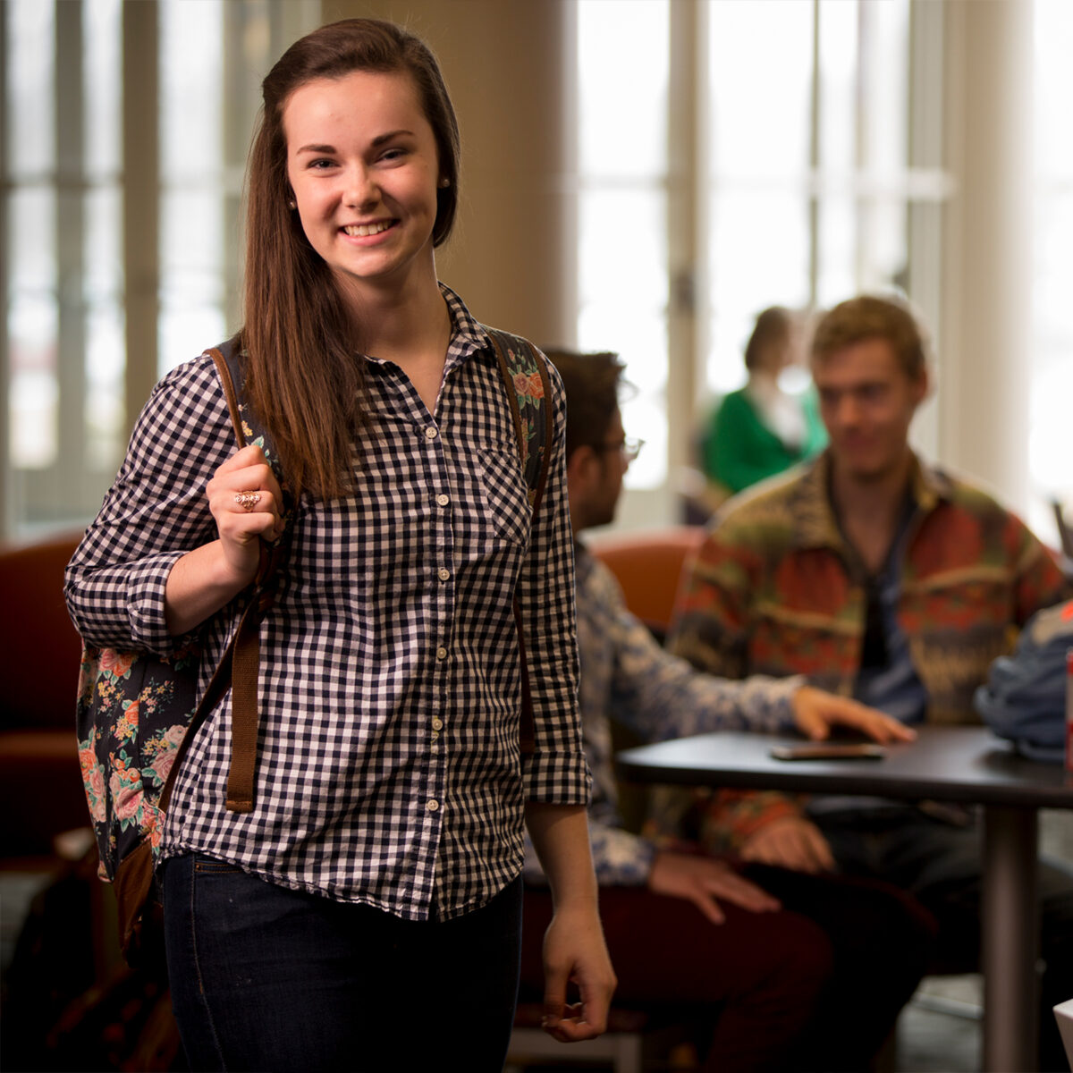 Girl in checkered shirt, holding a backpack