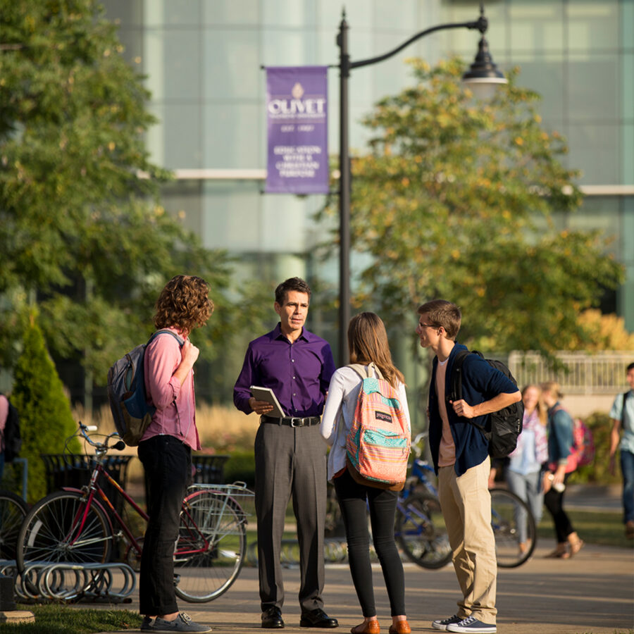 Group of students conversing with professor outside of Weber Center