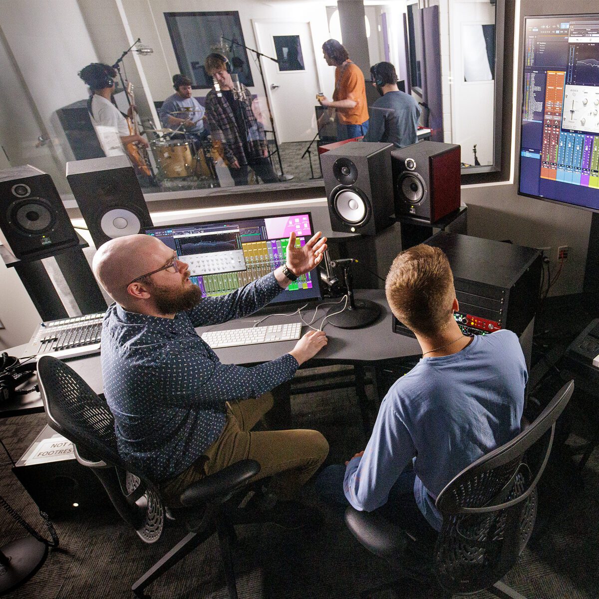 Student and faculty sit and the sound board