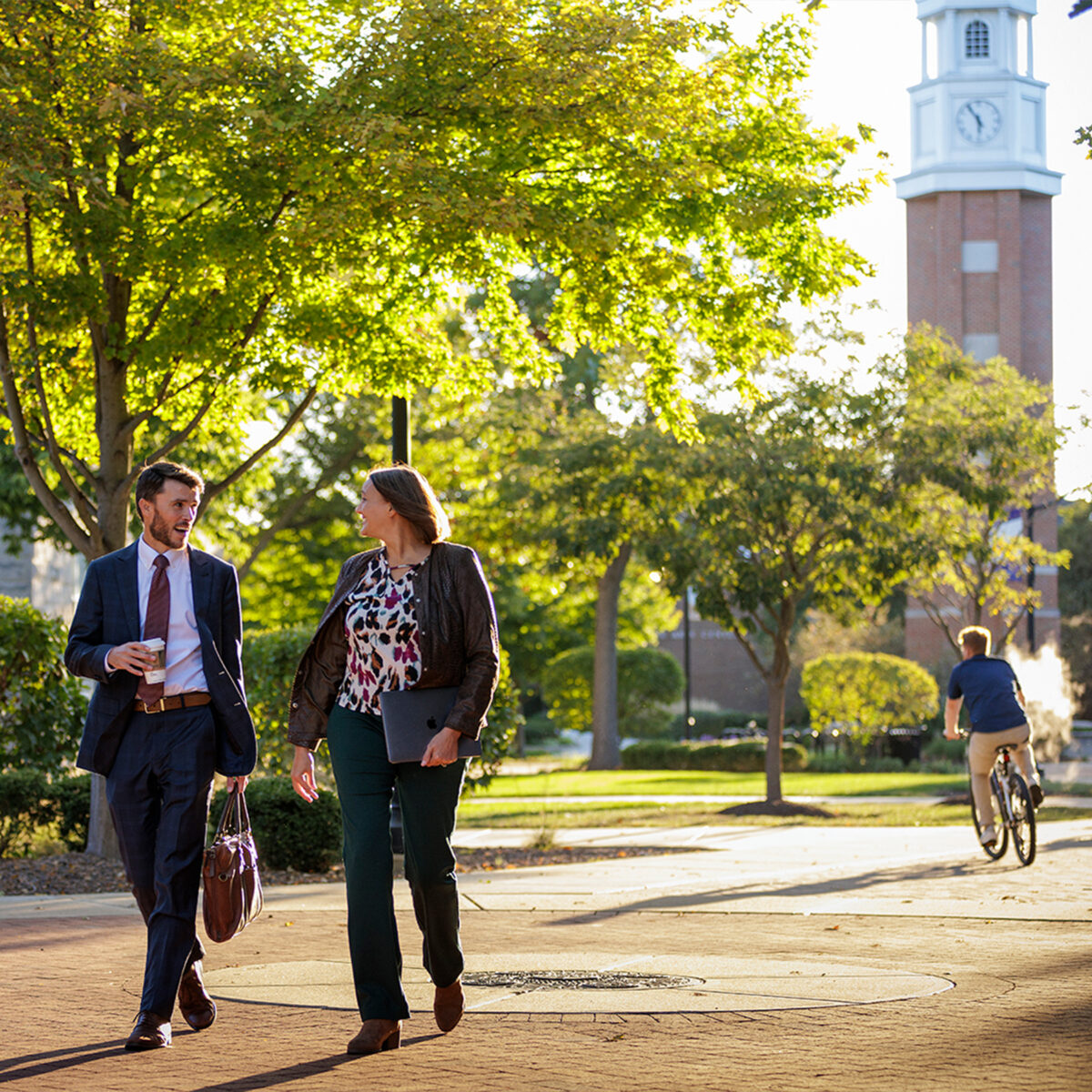 Two young professionals engaging in conversation as they walk through the Quad