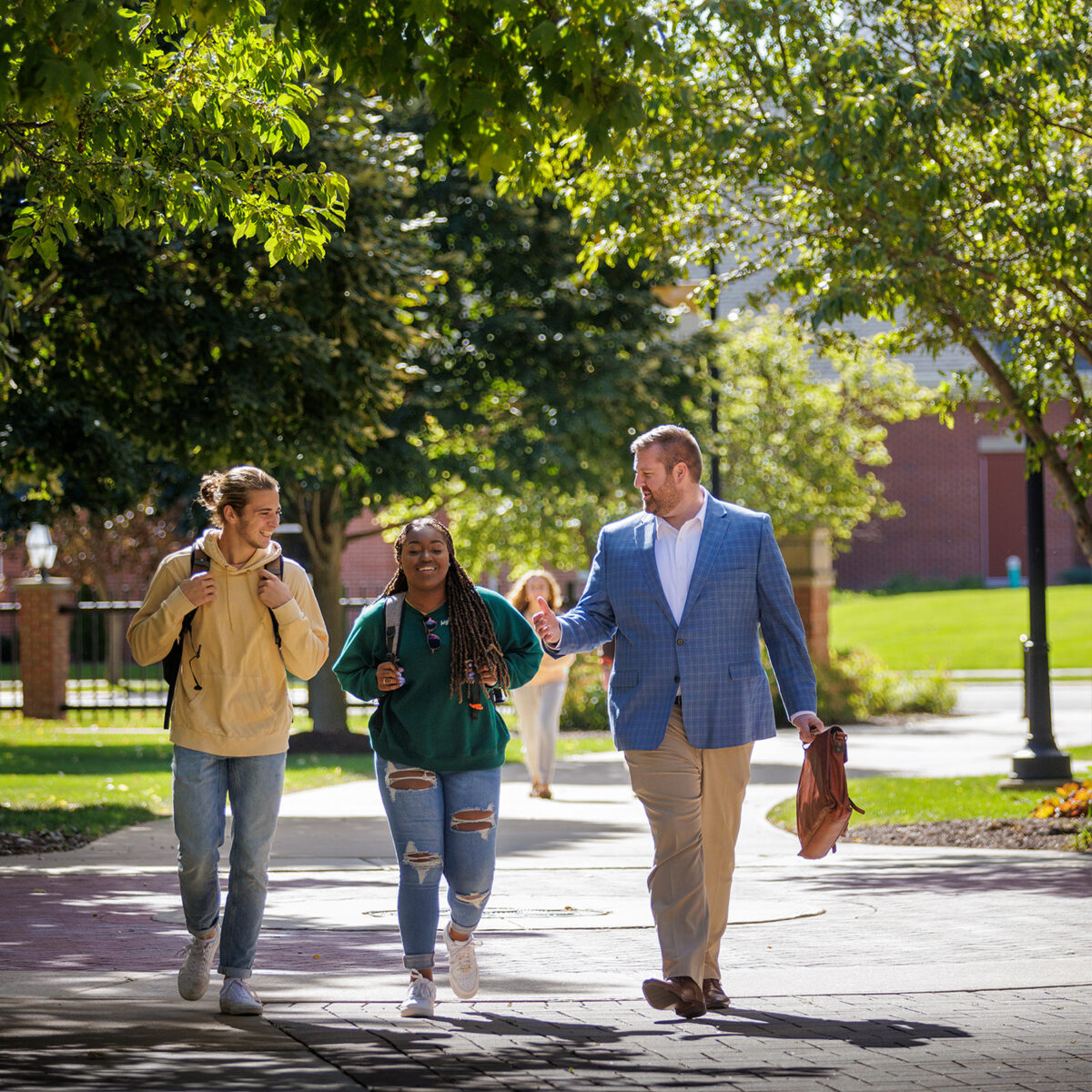 Young professionals walking through campus with Dr. Stephens