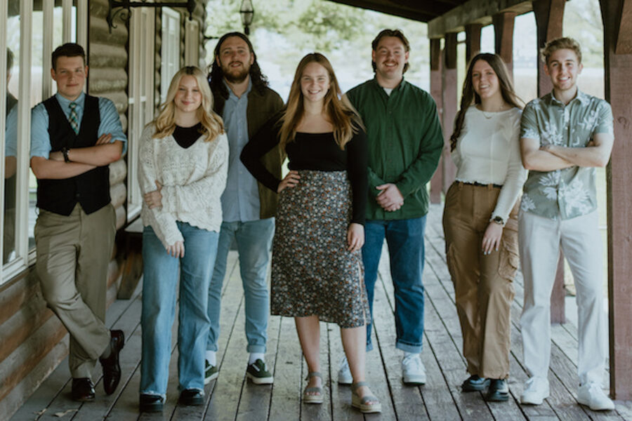 Ministry team poses outside a wooden cabin