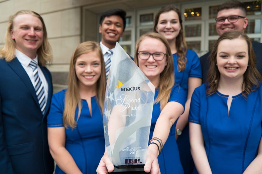 Enactus celebrating their win by holding their trophy