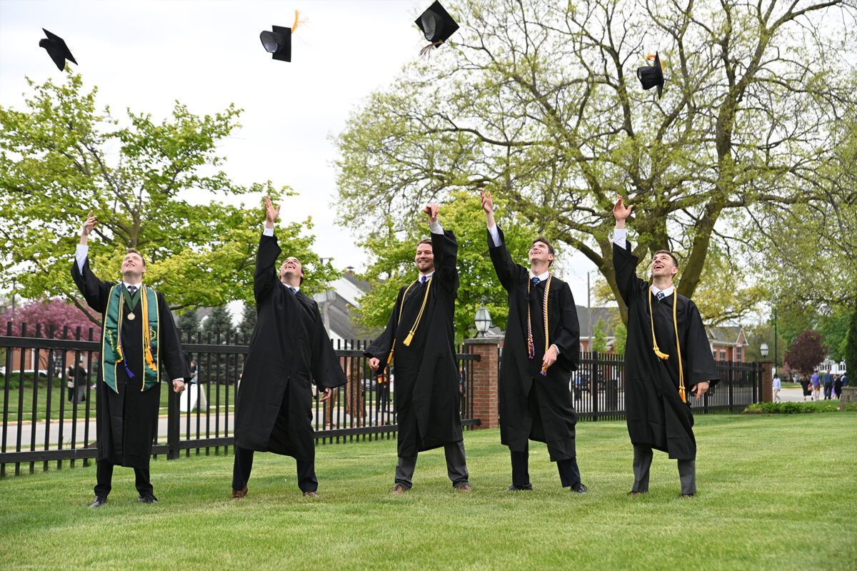 Boys throw their caps in the air after graduation