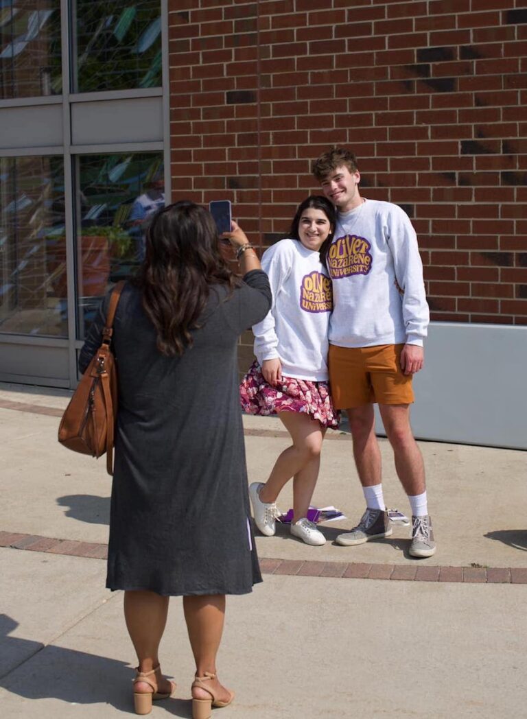 Students wearing Olivet sweatshirts posing for a photo in front of Centennial Chapel