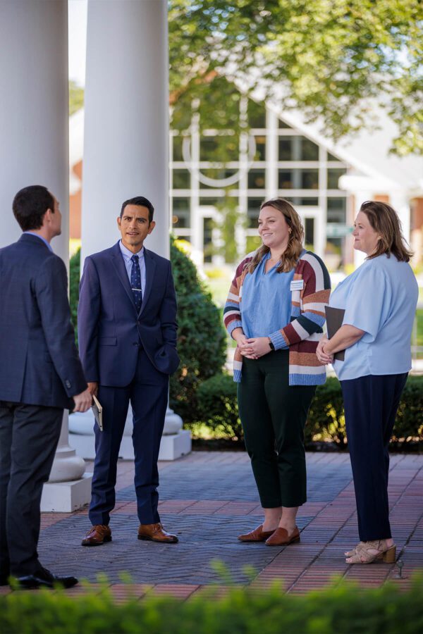 Group of faculty standing in a half circle while talking.