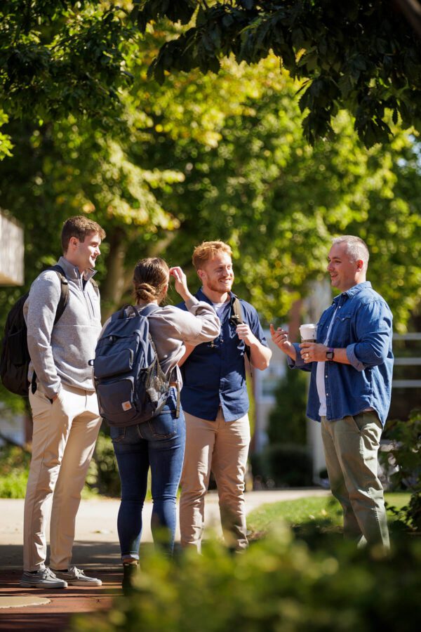 Group of students speaking with faculty in the Quad