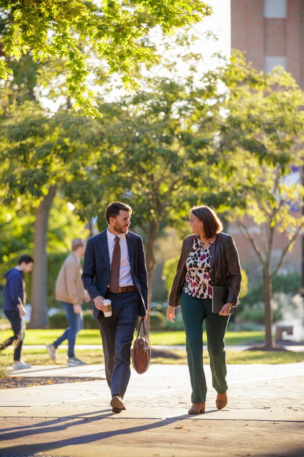 Two young professionals walking through campus