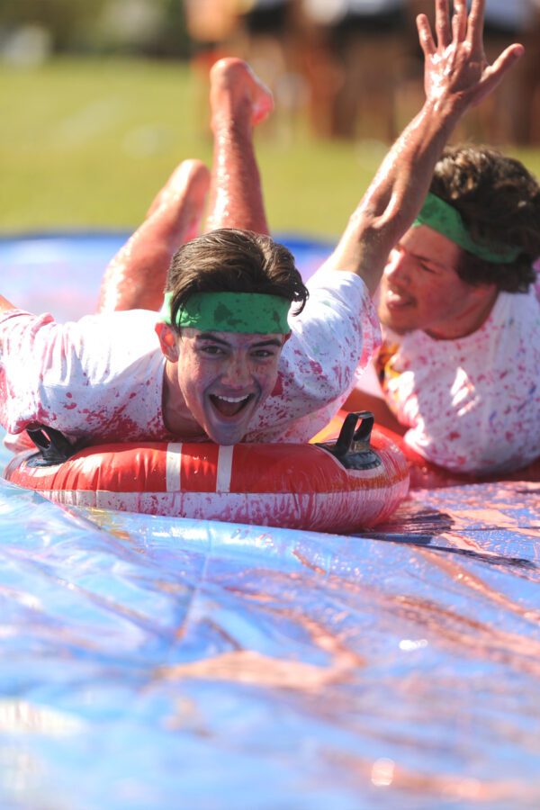 Two students sliding through color during Colors Wars