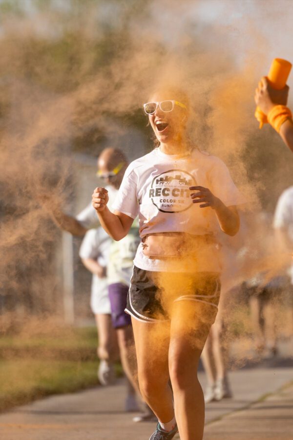 Student running through orange color during campus Color Run