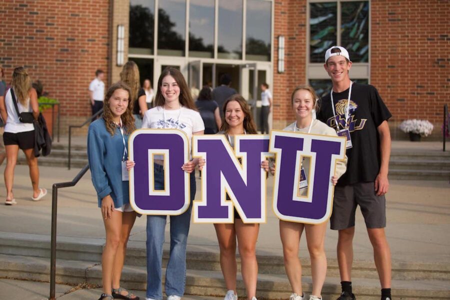 five students holding large O-N-U signs in front of Centennial Chapel