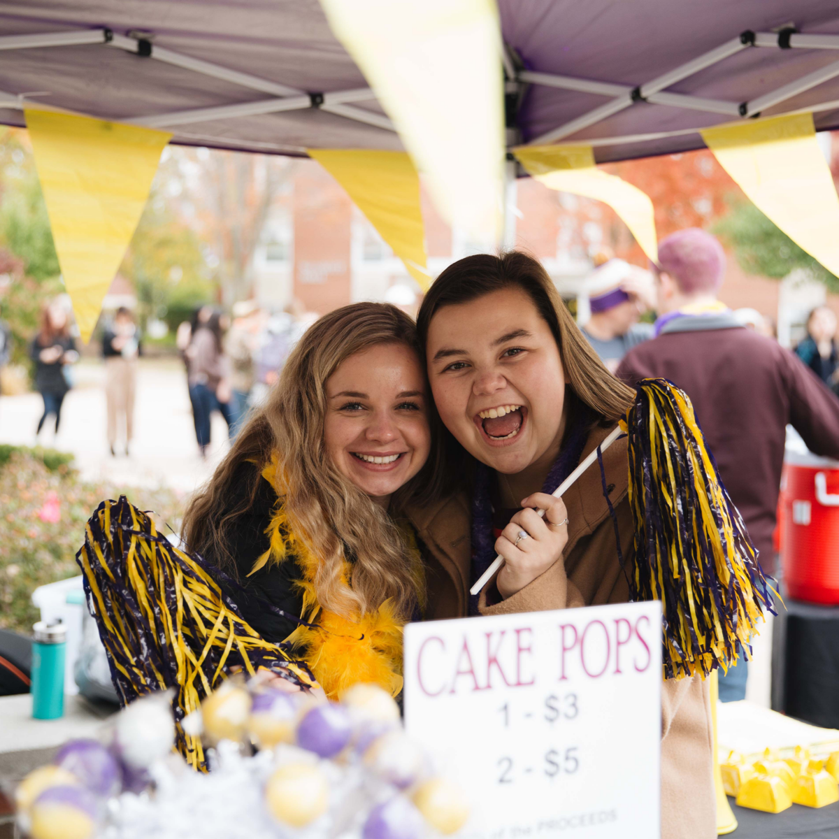 Two smiling girls at a Purple and Gold event