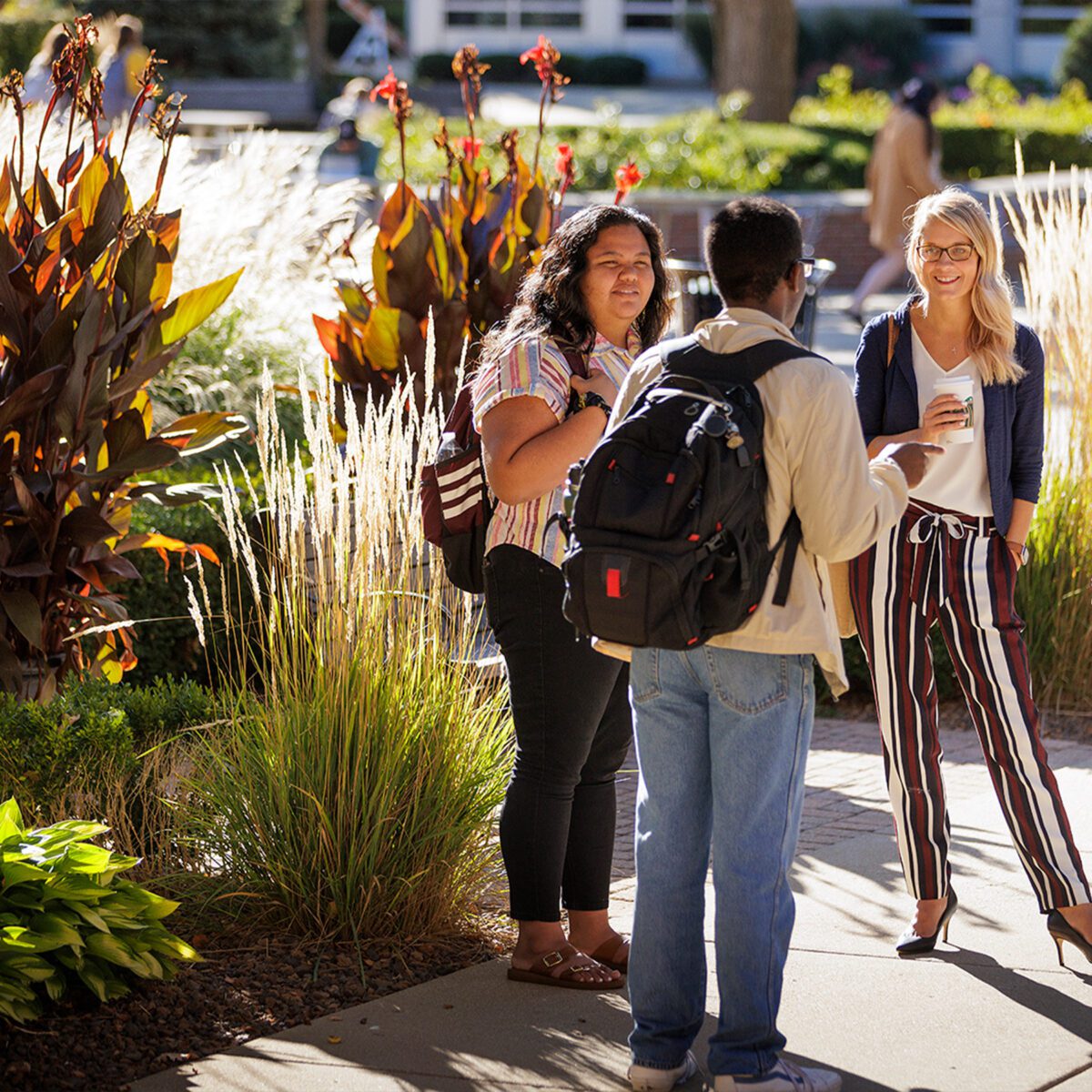 Photo of English professor having a conversation with two students