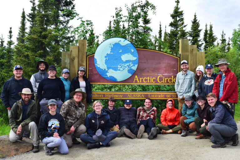 group photo in Alaska by arctic circle sign