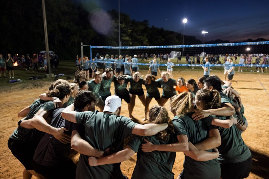 students in a circle on sand volleyball courts