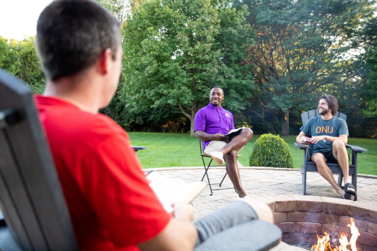 Tone Marshall leading a Bible study outside with two males