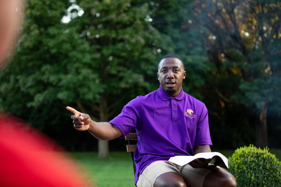 Tone Marshall sitting with an open Bible at a campfire