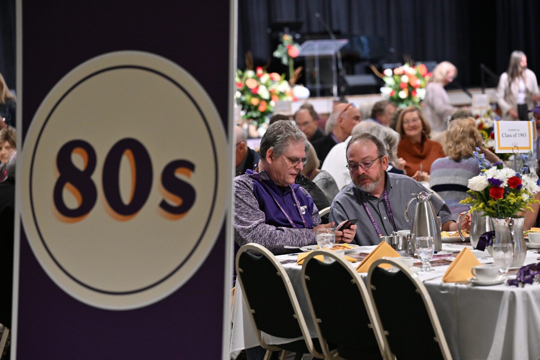 Two alumni sit at the reunion dinner for the class of '83.