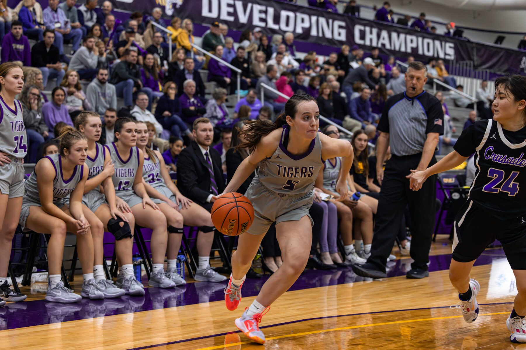 Olivet Women's Basketball player drives in with crowd watching behind her.