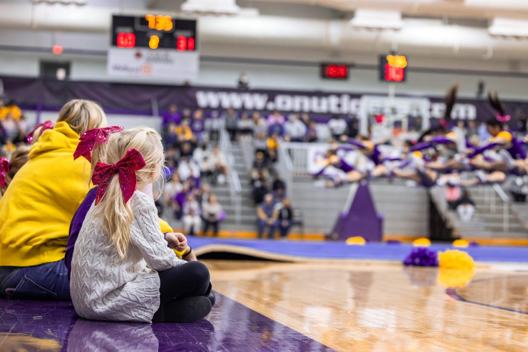 Two young kids watch the Olivet Cheerleaders do their performance.