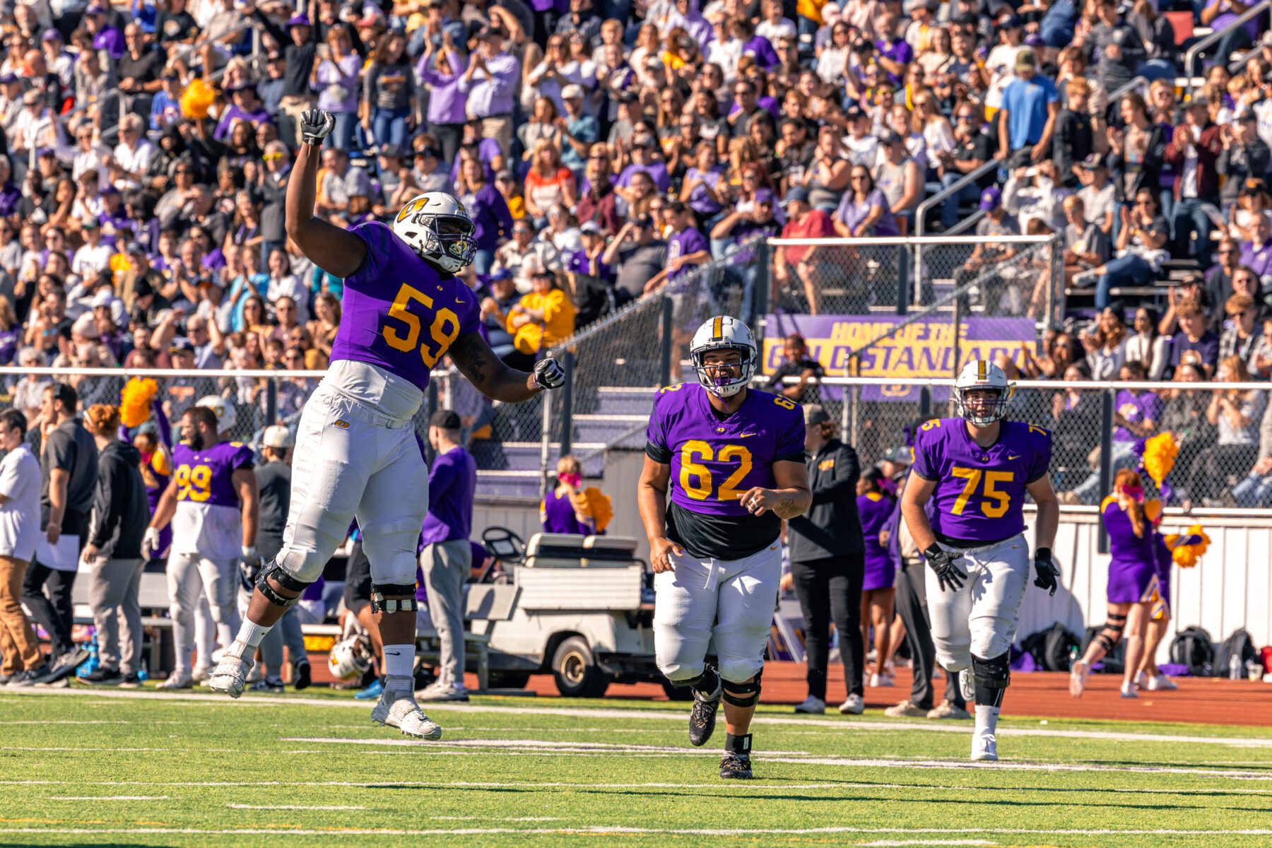 Olivet football players celebrate on the field, the crowd fills the background.