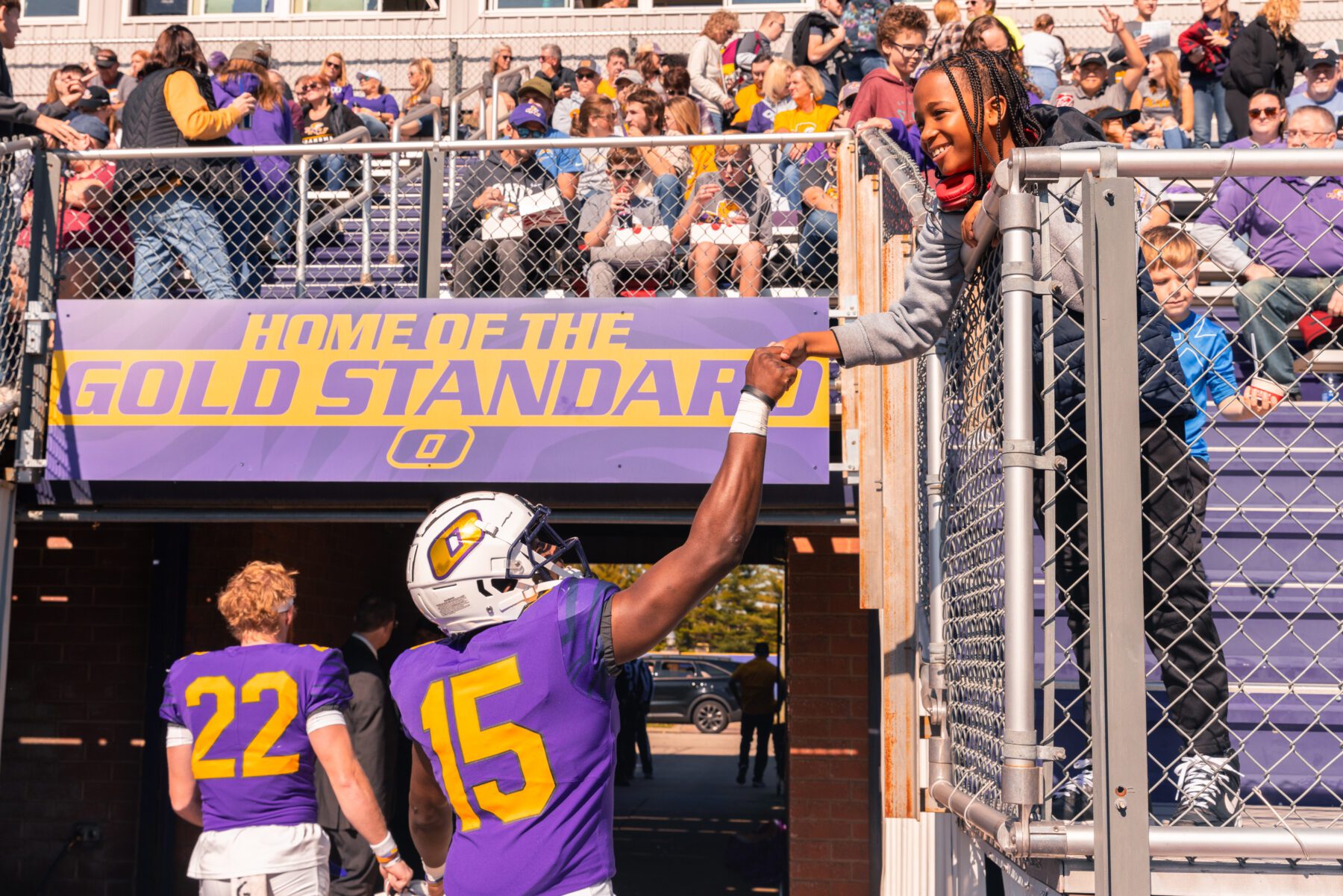 Olivet Football Player reaches to shake hands with a young girl.