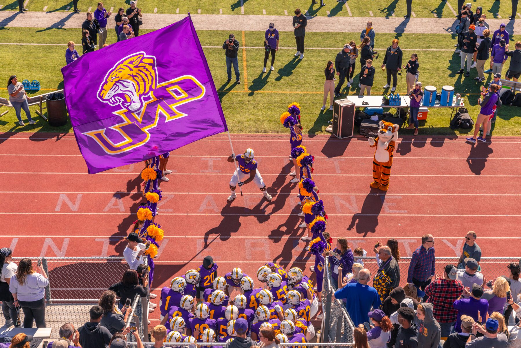 The Olivet Football team gathers to run out of the tunnel as an ONU flag waves through the air.
