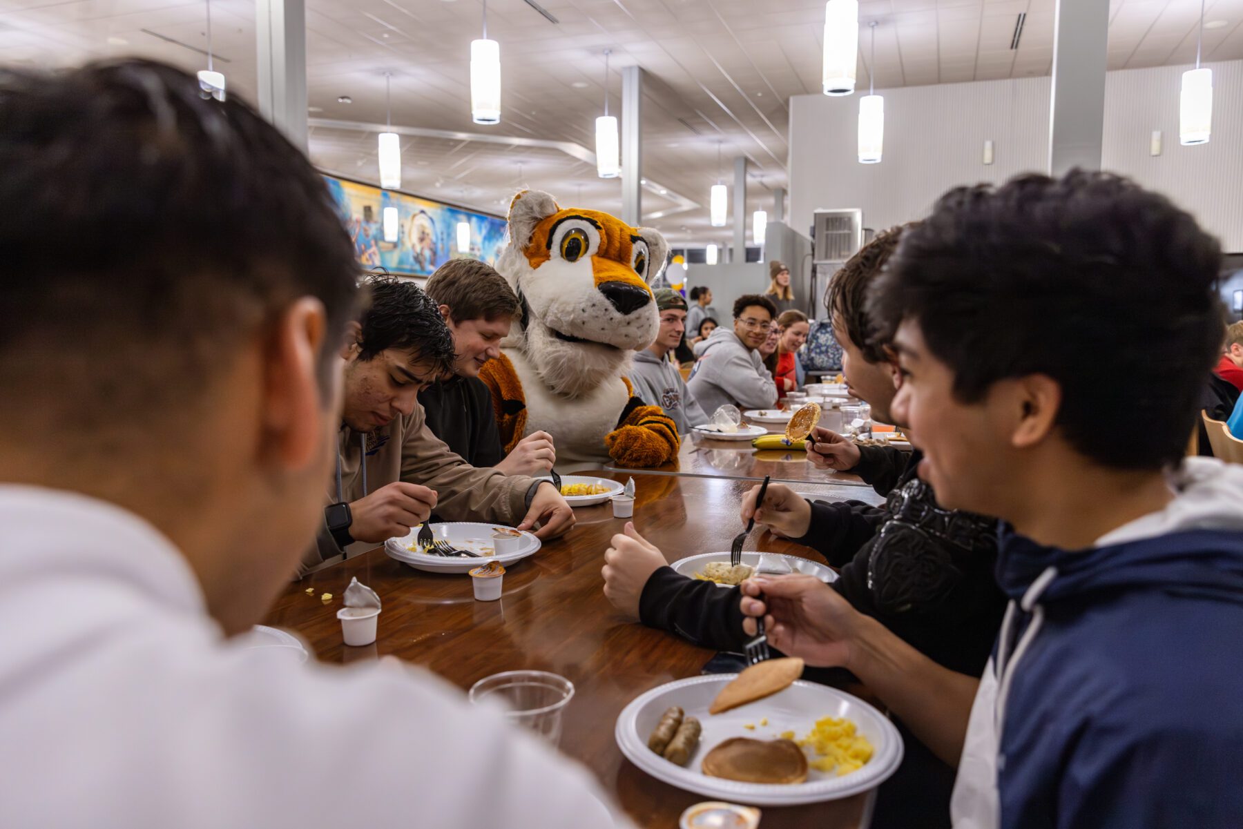 Students at the pancake feed enjoy their food with Toby the Tiger.