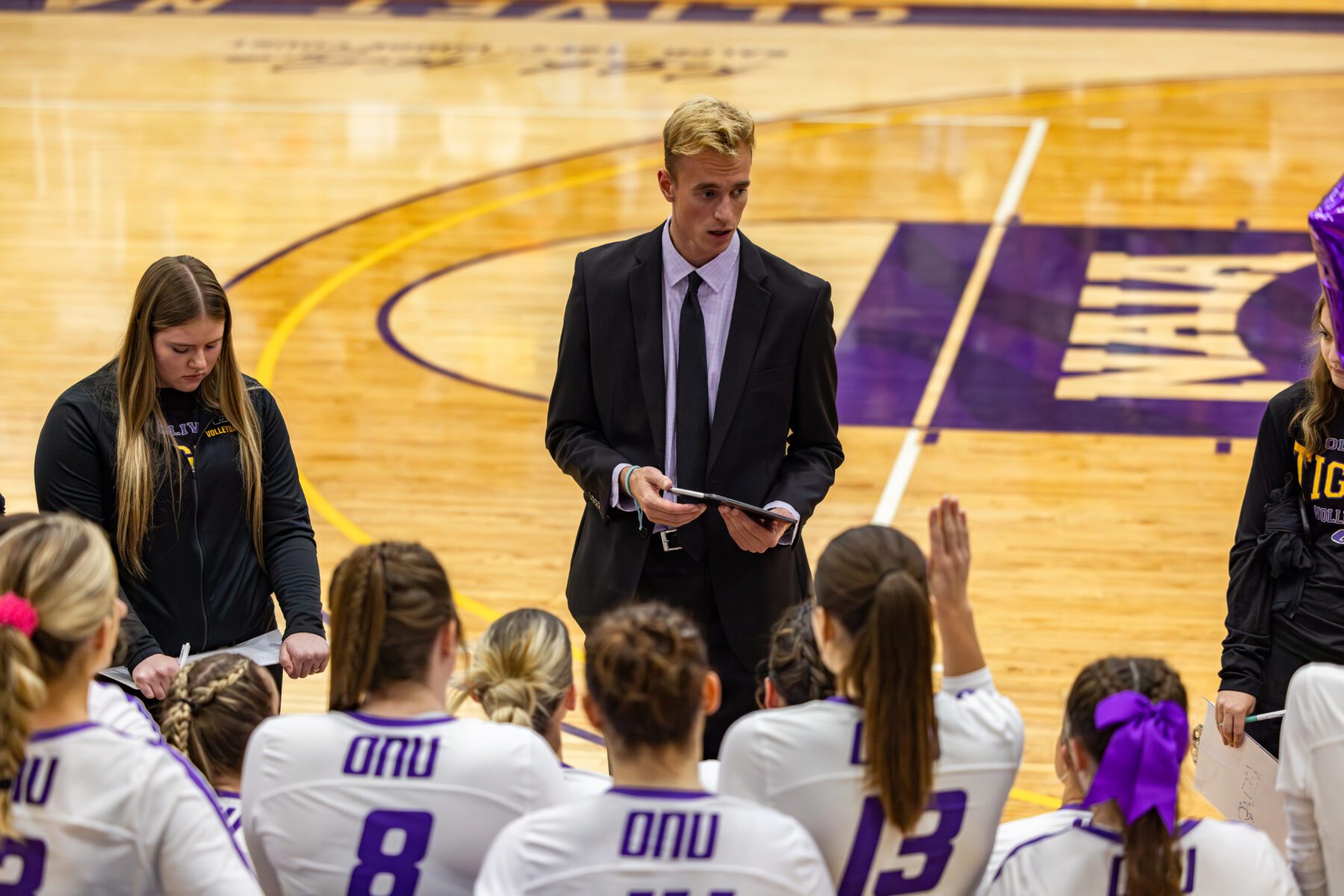 The women's head volleyball coach talks to the players inbetween sets.