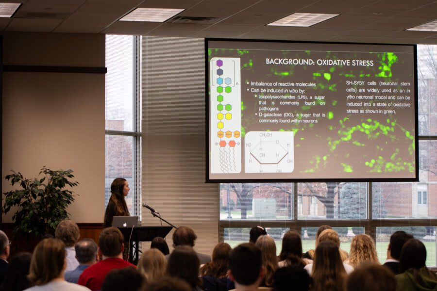 woman presenting scientific information in front of large screen