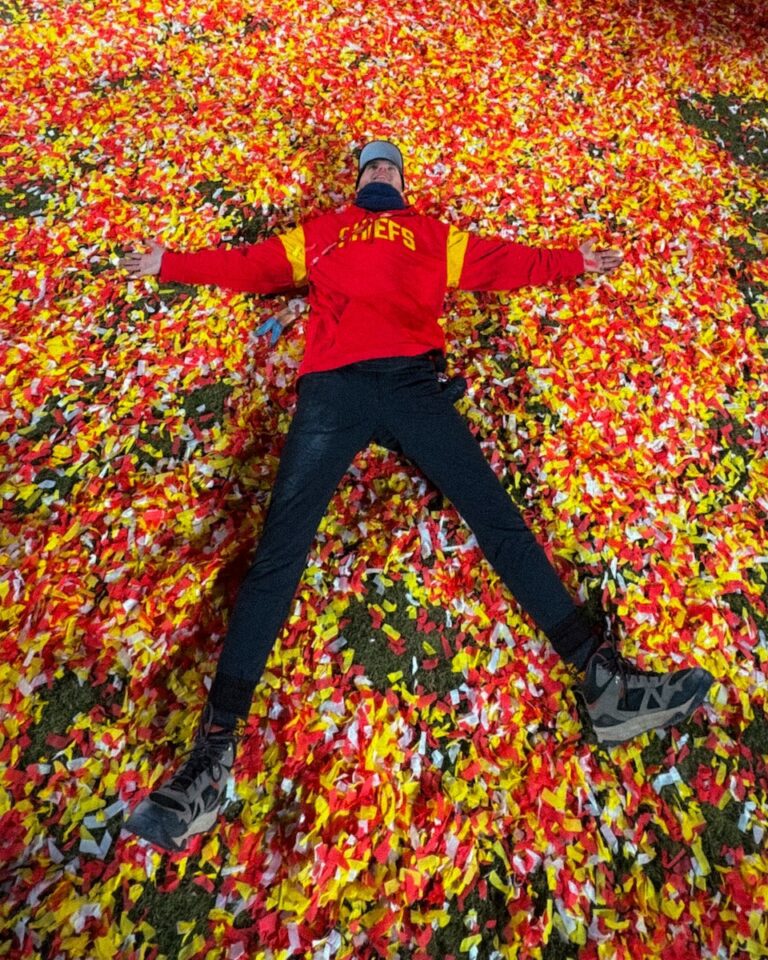 Kyle Petersen laying in red & yellow confetti after Chiefs win.