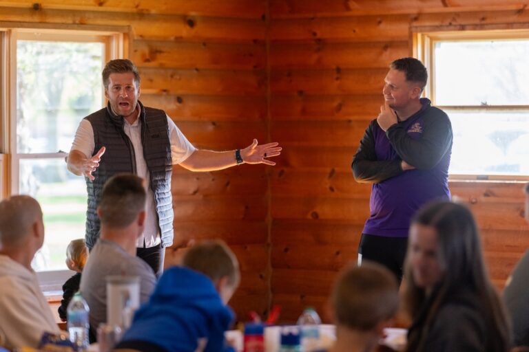 Two soccer coaches speaking to alumni group