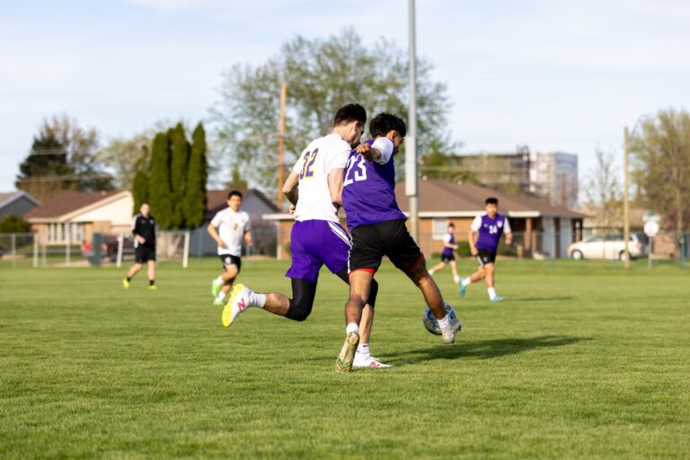 alumni men's soccer players kicking a ball