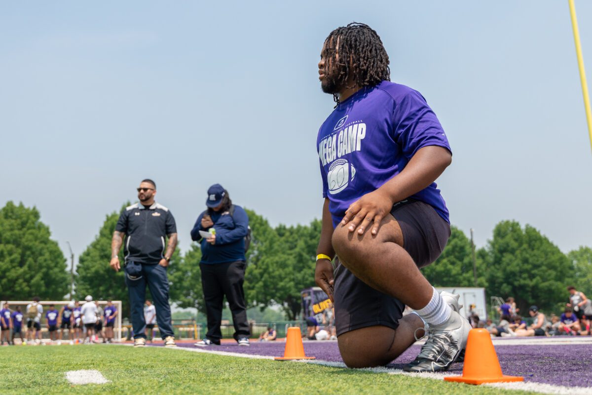Athlete kneels at the starting line while coaches evaluate drills at the 2025 Avante Mitchell Football Mega Camp at Olivet Nazarene University