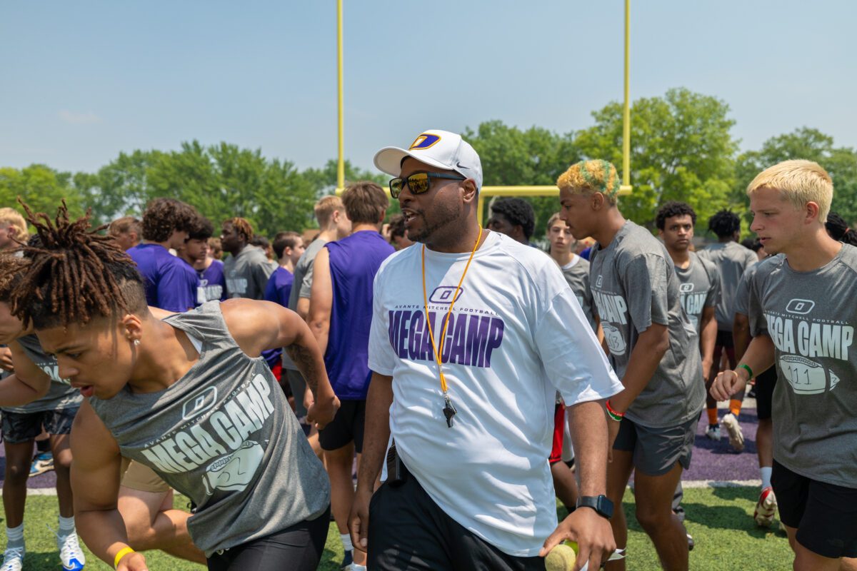 Coach oversees high school athletes warming up and preparing for drills at the 2025 Avante Mitchell Football Mega Camp at Olivet Nazarene University