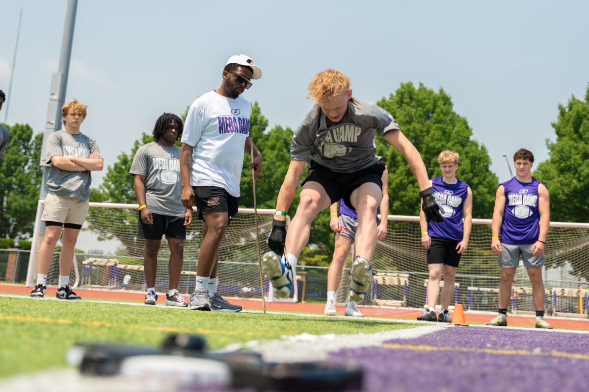 Athlete performs a vertical jump drill while coaches and peers observe at the 2025 Avante Mitchell Football Mega Camp at Olivet Nazarene University
