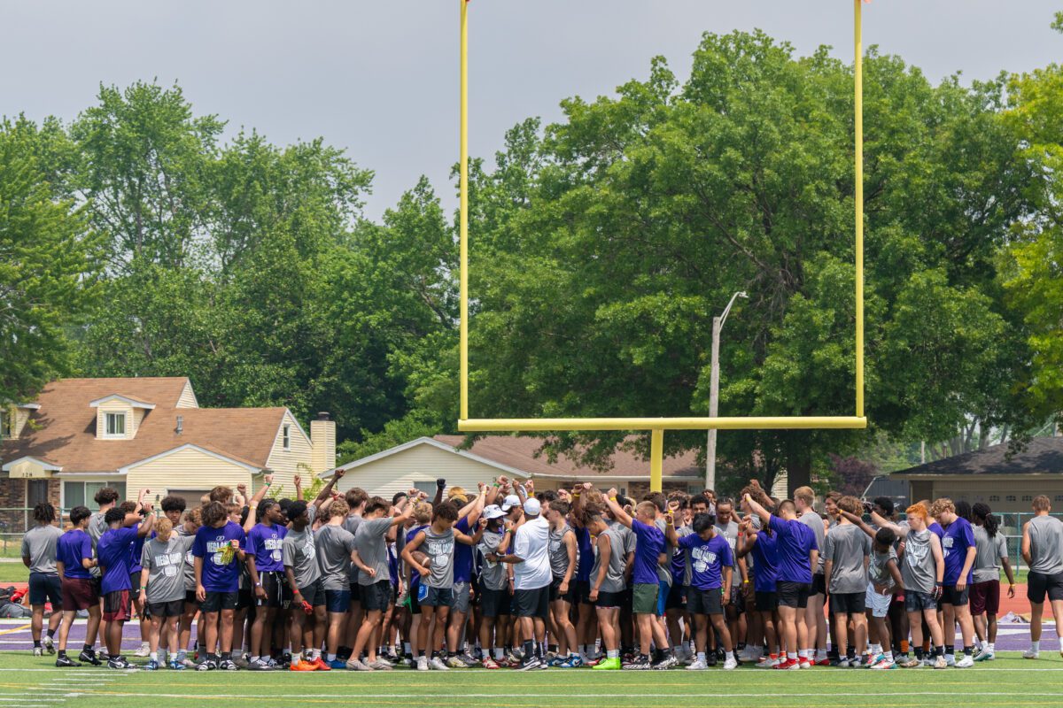 High school athletes and college coaches huddle on the field at the 2025 Avante Mitchell Football Mega Camp at Olivet Nazarene University