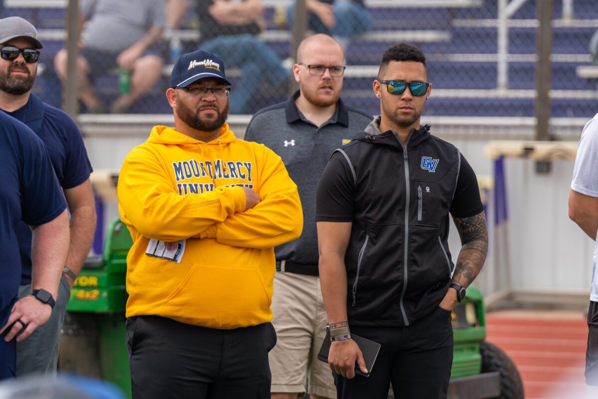 College football coaches from Mount Mercy University and Grand View University observe athletes during a recruiting event at a stadium.

