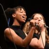 two girls holding a microphone and singing