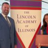 Dr. Jason Stephens and Grace Amburgey standing next to a banner of Lincoln Academy of Illinois