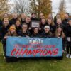 Olivet Women's Cross Country team holding their championship banner after their win.