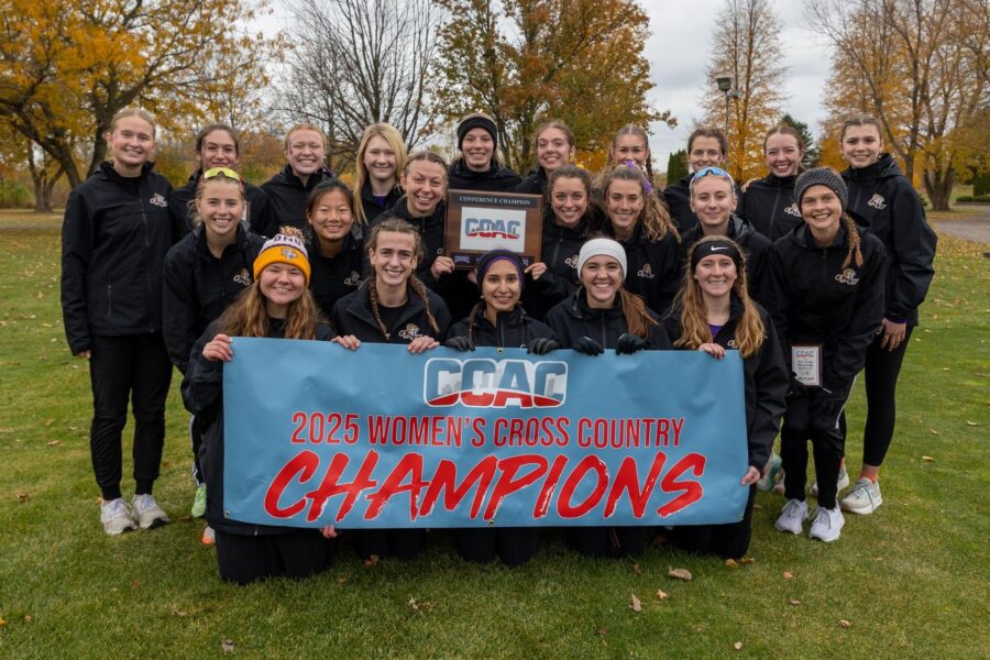Olivet Women's Cross Country team holding their championship banner after their win.